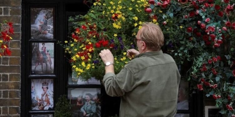 Un vecino de Windsor arregla las plantas, junto a fotos de la reina Isabel de Gran Bretaña, tras su muerte, en Windsor, Gran Bretaña, el 15 de septiembre de 2022. REUTERS/Paul Childs