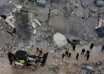 Los rescatistas se reúnen entre los escombros de los edificios derrumbados tras un terremoto, en la ciudad rebelde de Sarmada, Siria.