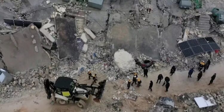 Los rescatistas se reúnen entre los escombros de los edificios derrumbados tras un terremoto, en la ciudad rebelde de Sarmada, Siria.