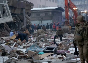 Un grupo de personas sobe escombros tratando de identificar víctimas debajo de ellos en Diyarbakir, Turquia.