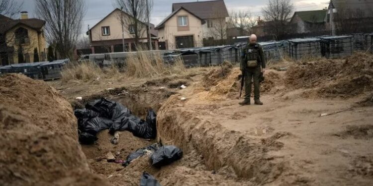 Un soldado ucraniano observa una fosa común con cadáveres de civiles, que según los residentes fueron asesinados por soldados rusos, en Bucha, en la región de Kiev (REUTERS Alkis Konstantinidis)