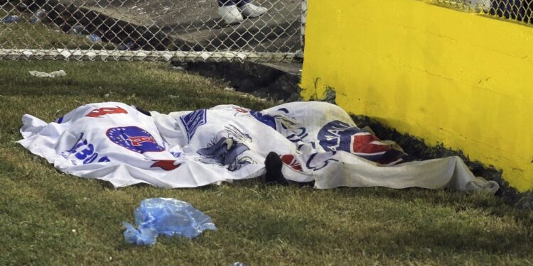 EDITORS NOTE: Graphic content / Victims' bodies are seen covered with Alianza's flags following a stampede during a football match between Alianza and FAS at Cuscatlan stadium in San Salvador, on May 20, 2023. Nine people were killed May 20, 2023 in a stampede at an El Salvador stadium where soccer fans had gathered to watch a local tournament, police said. (Photo by Milton FLORES / AFP)