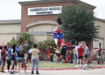 ALLEN, TEXAS - MAY 7: People watch as the construction of a wooden cross memorial is completed at the site of a fatal mass shooting a day earlier at Allen Premium Outlets on May 7, 2023 in Allen, Texas. According to reports, a shooter opened fire at the outlet mall, killing eight people. The gunman was then killed by an Allen Police officer responding to an unrelated call.   Stewart F. House/Getty Images/AFP (Photo by Stewart F. House / GETTY IMAGES NORTH AMERICA / Getty Images via AFP)