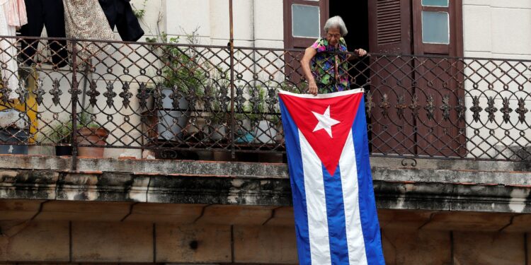 Una mujer sale al balcón donde se expone una bandera cubana, en La Habana, Cuba. EFE/Ernesto Mastrascusa/Archivo