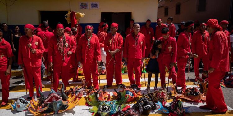 Un grupo de promeseros participan en la celebración religiosa de los Diablos Danzantes de Yare hoy, en San Francisco de Yare, estado Miranda (Venezuela). Cientos de creyentes marcharon este jueves en Venezuela en una procesión centenaria, conocida como los "Diablos Danzantes de Yare", con la que penitentes vestidos de rojo y con el rostro cubierto con máscaras estrafalarias celebran el triunfo del bien sobre el mal en el marco de la festividad católica del Corpus Christi. EFE/ Rayner Peña R.