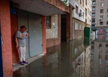 Una mujer se para junto a la entrada de su casa en una calle inundada, tras la rotura de la presa de Nova Kakhovka en Jersón, Ucrania, el 6 de junio. (Crédito: Alina Smutko/Reuters)