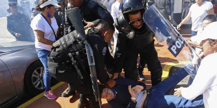 An anti-government protester is dragged away and arrested by police as security forces disrupt an opposition march coined "United for Freedom" in Managua, Nicaragua, Sunday, Oct. 14, 2018. Anti-government protests calling for President Daniel Ortega's resignation are ongoing since April, triggered by a since-rescinded government plan to cut social security pensions. Ortega said opponents will have to wait until his term ends in 2021. (AP Photo/Alfredo Zuniga)