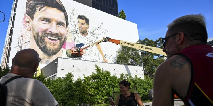 (FILES) People watch as Argentine artist Maximiliano Bagnasco paints a mural of international soccer star Lionel Messi in Wynwood, Miamis art district, in Miami, Florida on July 10, 2023. Messi has signed a contract until 2025 with Inter Miami, the Major League Soccer team announced on July 15, 2023.. (Photo by CHANDAN KHANNA / AFP) / RESTRICTED TO EDITORIAL USE - MANDATORY MENTION OF THE ARTIST UPON PUBLICATION - TO ILLUSTRATE THE EVENT AS SPECIFIED IN THE CAPTION