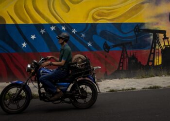 AME6708. CARACAS (VENEZUELA), 31/07/2023.- Un motociclista pasa frente a un mural en el Complejo MinPetróleo - Petróleos de Venezuela S.A. (Pdvsa), el 27 de julio de 2023 en Caracas (Venezuela). La gallina de los huevos de oro de Venezuela, la industria petrolera, ha estado sobre el tapete en las últimas semanas, cuando candidatos a las primarias opositoras han debatido sobre si convendrá o no su privatización, una opción que algunos aspirantes tienen como meta en caso de llegar a la Presidencia. EFE/ MIGUEL GUTIÉRREZ