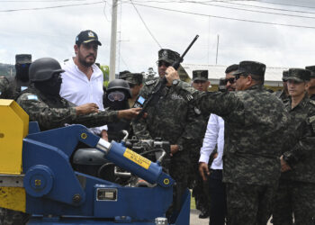 Defense Minister Jose Manuel Zelaya (2nd-L) watches as members of the army proceed to destroy high-powered firearms seized from Barrio 18 and Mara Salvatrucha (MS-13) gangs in Honduran prisons after President Xiomara Castro ordered to take control of them, at the headquarters of the Military Police of Public Order in Tegucigalpa on July 10, 2023. (Photo by Orlando SIERRA / AFP)