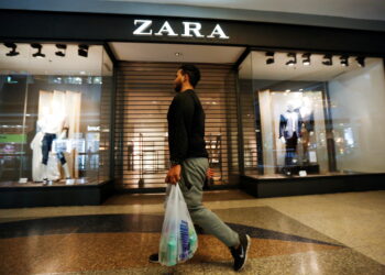 FILE PHOTO: A man walks past a Zara retail store, with its shutters drawn, at a mall in Caracas September 30, 2014. REUTERS/Carlos Garcia Rawlins