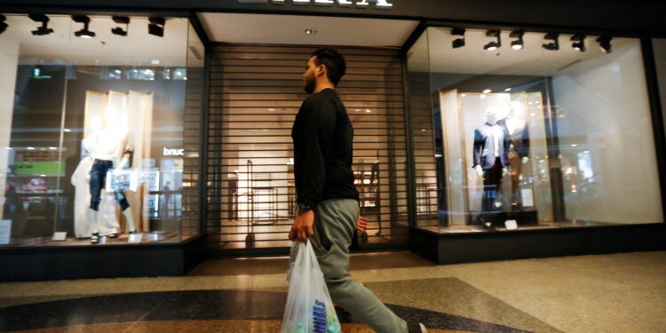 FILE PHOTO: A man walks past a Zara retail store, with its shutters drawn, at a mall in Caracas September 30, 2014. REUTERS/Carlos Garcia Rawlins