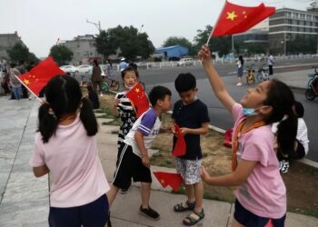 Niños ondean banderas nacionales chinas en la calle (REUTERS/Tingshu Wang)