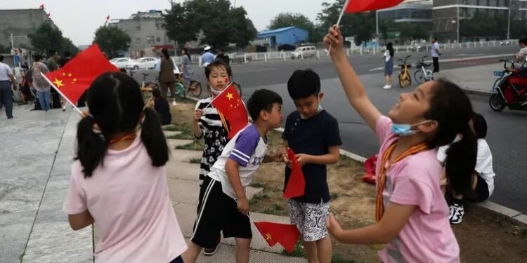 Niños ondean banderas nacionales chinas en la calle (REUTERS/Tingshu Wang)