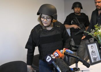 Veronica Sarauz, wife of slain Ecuadorean presidential candidate Fernando Villavicencio, wears a protective helmet and a bulletproof vest before speaking during a press conference in Quito on August 12, 2023. Ecuador declared a state of emergency on August 10 and asked the FBI to help probe the assassination on Wednesday of popular presidential candidate Villavicencio, whose death has highlighted the once-peaceful nation's decline into a violent hotbed of drug trafficking and organized crime. (Photo by Rodrigo BUENDIA / AFP)