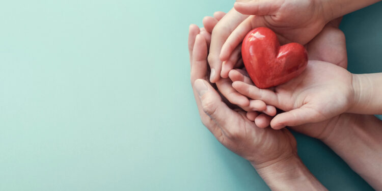 adult and child hands holding red heart on aqua background, heart health, donation, CSR concept, world heart day, world health day, family day