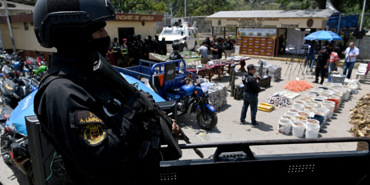 A member of the Anti-Extortion and Kidnapping Group (CONAS) stands guard as confiscated weapons and ammunition are displayed during a press conference after authorities seized control of the prison in Tocoron, Aragua State, Venezuela, on September 21, 2023. Venezuela said Wednesday it had seized control of a prison from the hands of a powerful gang with international reach, in a major operation involving 11,000 members of its security forces. (Photo by YURI CORTEZ / AFP)