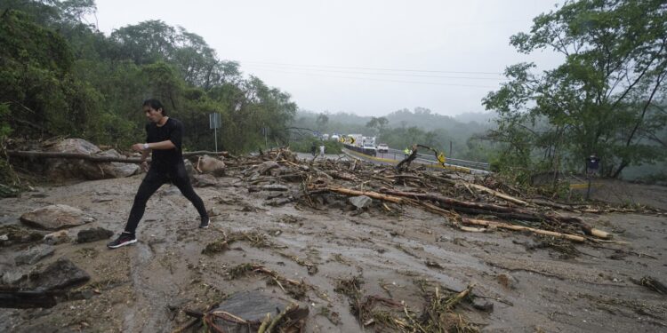 Un hombre cruza una carretera bloqueada por un deslizamiento de tierra causado por el huracán Otis, el miércoles 25 de octubre de 2023, cerca de Acapulco, México. (AP Foto/Marco Ugarte)