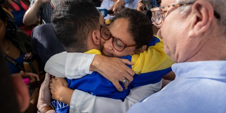 AME6133. CARACAS (VENEZUELA), 23/12/2023.- Wendelin Peña (c) abraza a su hijo, el estudiante universitario John Álvarez, luego de que este saliera en libertad de un centro de reclusión de la Policía Nacional Bolivariana (PNB) hoy, en Caracas (Venezuela). Las autoridades de Venezuela liberaron este sábado a Álvarez, preso desde el pasado 30 de agosto -acusado de conspiración y asociación para delinquir-, tras lo cual fue sometido a "torturas", según organizaciones de derechos humanos. El joven universitario, cuya salida del centro de detención fue corroborada por EFE, se une a la treintena de "presos políticos" que fueron puestos en libertad el pasado jueves, tras lo cual quedan, al menos, 265 personas privadas de la libertad por sus críticas al Ejecutivo, según los registros de varias ONG y de la coalición opositora Plataforma Unitaria Democrática (PUD). EFE/ Rayner Peña R.