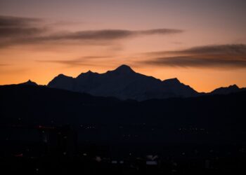 This photograph taken on December 24, 2023, shows The Mont-Blanc massif silhouetted on sun rises from Nyon, in Haute-Savoie. (Photo by Fabrice COFFRINI / AFP)