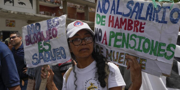Un maestro lleva carteles durante una protesta docente por mejores salarios y beneficios en Caracas, Venezuela, el lunes 18 de septiembre de 2023. (AP Foto/Ariana Cubillos)