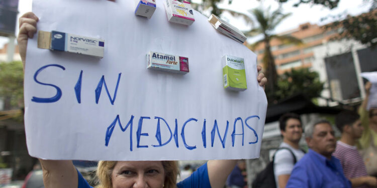 A woman holds up a sign that reads in Spanish "Without medicine" during a protest against a shortage of medicine and medical supplies in Caracas, Venezuela, Wednesday, April 13, 2016. The country's private, opposition-leaning pharmaceutical association says Venezuela only has 20 percent of the medications it requires, a result of currency and price controls. The government blames the shortages on "economic war" waged by its right-wing opponents. (AP Photo/Ariana Cubillos)