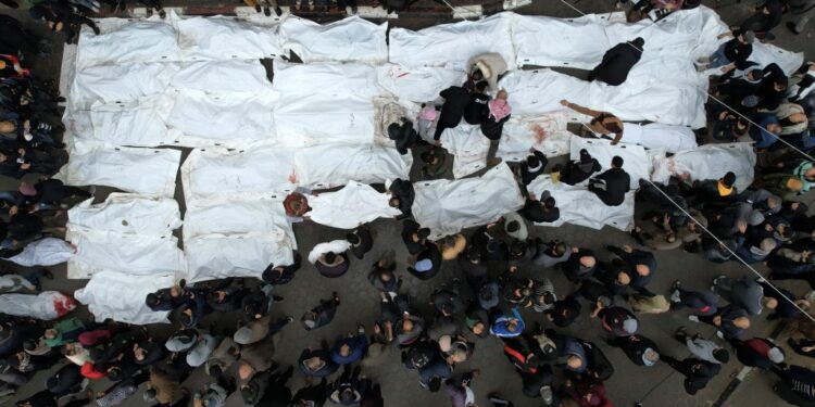 An aerial view shows Palestinians mourning their relatives, killed in an overnight Israeli strike on the Al-Maghazi refugee camp, during a mass funeral at the Al-Aqsa hospital in Deir Al-Balah, in the central Gaza Strip, on December 25, 2023, amid ongoing battles between Israel and the Palestinian militant group Hamas. (Photo by MAHMUD HAMS / AFP)