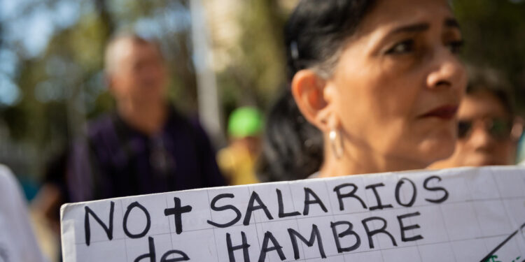 CARACAS (VENEZUELA), 09/01/2023.- Una mujer sostiene una pancarta que dice "No más salarios de hambre" durante una protesta para exigir aumento salarial y de pensiones, hoy, en Caracas (Venezuela). Cientos de trabajadores públicos protestaron este martes en Caracas y en buena parte de Venezuela contra los "salarios de hambre" que aseguran devengar, y para exigir ingresos "dignos" que les permitan cubrir sus necesidades básicas, así como por el "hostigamiento laboral". EFE/ Rayner Peña R.