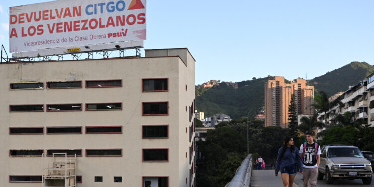 FILE PHOTO: People walk past a billboard that reads "Give Citgo back to the Venezuelans. Vice Presidency of the working class PDVSA", in Caracas, Venezuela November 28, 2023. REUTERS/Gaby Oraa/File Photo