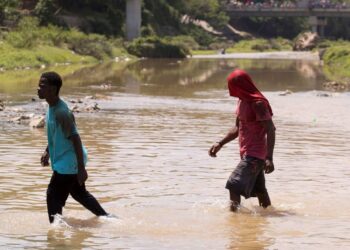 Dos haitianos cruzan el río Masacre, la frontera natural entre República Dominicana y Haití. EFE