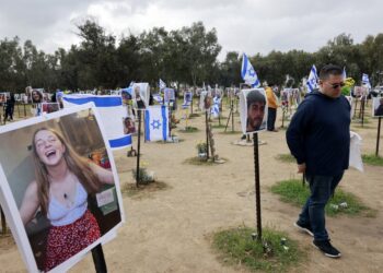 A man walks past portraits of Israeli people taken captive or killed by Hamas militants during the October 7 attacks, during a visit at the site where the Supernova music festival took place near Kibbutz Reim in southern Israel, on January 14, 2024, after 100 days of war between Israel and the militant Hamas group in Gaza. (Photo by Menahem Kahana / AFP)