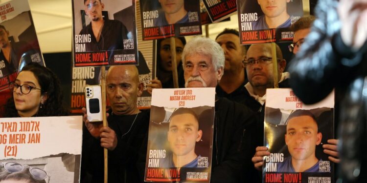 Relatives and supporters hold placards bearing portraits of Israeli hostages held in Gaza since the October 7 attacks by Hamas in southern Israel, during a rally calling for their release and marking their nearly 100 days of captivity, in Tel Aviv on January 13, 2024. The placards (front) show Matan Angrest, 21. (Photo by AHMAD GHARABLI / AFP)