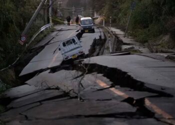 Varios transeúntes observan los daños en una carretera cercana a la ciudad de Noto, en la península de Noto (AP Foto/Hiro Komae)
