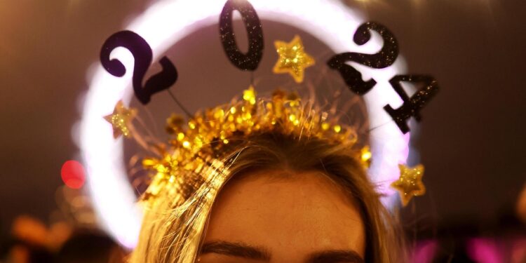 Londres (Reino Unido), 31/12/2023.- Una mujer con una diadema de 2024 celebra la llegada del Año Nuevo en la rivera del río Támesis en Londres, Reino Unido. EFE/ Neil Hall