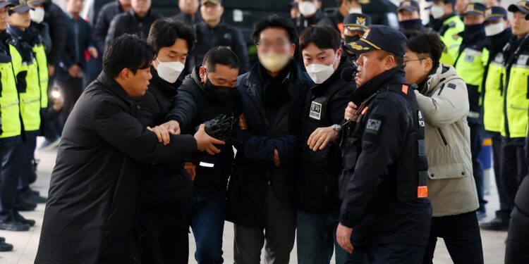 Busan (Korea, Republic Of), 02/01/2024.- A man (C, blurred) is taken by police investigators from Gangseo Police Station to Busan Metropolitan Police Agency in Busan, South Korea, 02 January 2024. The man in his 60s stabbed the left side of the neck of Lee Jae-myung, head of the main opposition Democratic Party, during the latter's visit to the construction site of an airport on Gadeok Island off Busan earlier in the day. (Corea del Sur) EFE/EPA/YONHAP SOUTH KOREA OUT 
IMAGE PIXELATED AT SOURCE