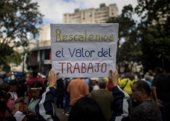 AME632. CARACAS (VENEZUELA), 18/01/2024.- Una persona muestra un cartel de protesta durante una manifestación de trabajadores que exigen mejores salarios y condiciones laborales, el 15 de enero de 2024, en Caracas (Venezuela). Los trabajadores públicos de Venezuela inician otro año de protestas contra los "salarios de hambre", una lucha que planean intensificar hasta que el clamor por un ingreso que satisfaga sus necesidades reciba, finalmente, una respuesta de las autoridades acorde a sus demandas, dijeron sindicalistas a EFE. Cientos de trabajadores llevaron a cabo el lunes la segunda jornada de manifestaciones de 2024, que finalizó con el anuncio del presidente Nicolás Maduro de un aumento de 30 a 60 dólares de una bonificación mensual sin incidencia en el cálculo de beneficios como las prestaciones, mientras que el salario mínimo se mantiene, desde marzo de 2022, en 130 bolívares, hoy 3,6 dólares al mes. EFE/ Miguel Gutiérrez