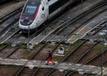An employee walks on the Charenton-le-pont railway yard near an InOui high-speed TGV train, amid a ticket controller strike in Paris on February 16, 2024. Train stations anticipate possible chaos for the school holiday weekend: only one in two TGVs will run from February 16 to 18, 2024, due to a controllers' strike, according to the SNCF. (Photo by Ian LANGSDON / AFP)