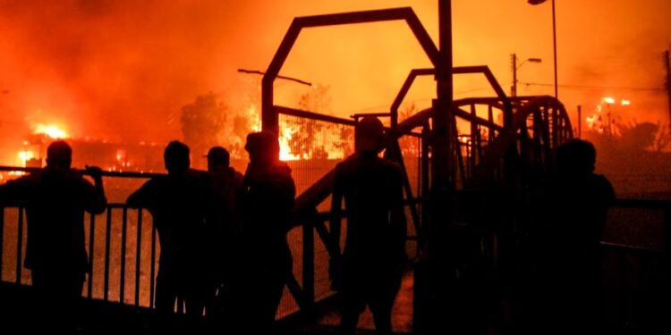 Un grupo de vecinos observa mientras las llamas devoran un edificio en Viña del Mar. (AP/Cristobal Basaure)AP