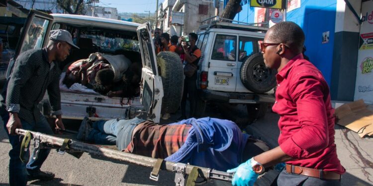 EDITORS NOTE: Graphic content / Paramedics carry the body of a person who was among a dozen killed in the street by gang members, in Pétionville, Port-au-Prince, Haiti, March 18, 2024. The UN children's agency chief offered a dire assessment March 17, 2024 of the chaotic situation in Haiti, saying it was "almost like a scene out of 'Mad Max,'" which depicted a violent and lawless post-apocalyptic future. (Photo by Clarens SIFFROY / AFP)