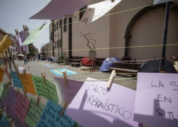 A picture taken in La Laguna on the Spanish Canary island of Tenerife, on April 13, 2024 shows signs written by protesters next to tents of activists on hunger strike to protest against mass tourism infrastructures. Activists started hunger strike on April 11 to demand a moratorium on mass tourism on the Canary Islands. (Photo by DESIREE MARTIN / AFP)