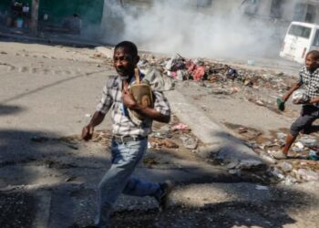 Hombres corren a refugiarse mientras la policía antidisturbios lanza gases lacrimógenos en un esfuerzo por dispersar a la gente cerca del Palacio Nacional, en Puerto Príncipe, Haití, el martes 2 de abril de 2024. [Foto: Archivo/AP].