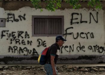 Un hombre delante de un grafiti firmado por la guerrilla del ELN en Cúcuta, que dice “Fuera Tren de Aragua”.