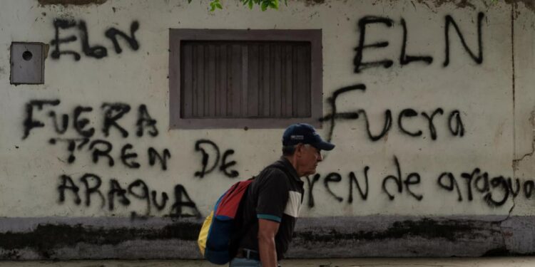 Un hombre delante de un grafiti firmado por la guerrilla del ELN en Cúcuta, que dice “Fuera Tren de Aragua”.