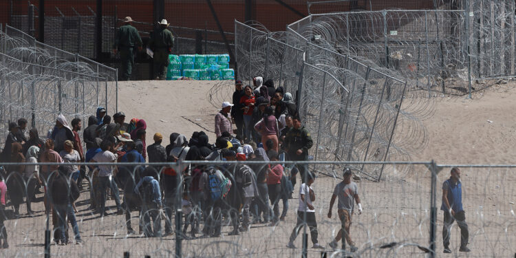 MEX4905. CIUDAD JUÁREZ (MÉXICO), 18/04/2024.- Fotografía aérea que muestra a migrantes en la frontera con Estados Unidos, este jueves en Ciudad Juárez (México). Unos 400 migrantes lograron entrar por la fuerza hasta el muro entre Juárez y El Paso este jueves, tras atravesar la alambrada de navajas y superar a un grupo de agentes de la Guardia Nacional, para luego ser procesados por el departamento de Migración de Estados Unidos. EFE/Luis Torres.