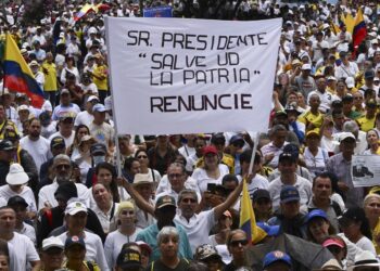 A demonstrator holds a sign that reads "Mr. President, save the homeland. Resign" during a protest against the government of Colombian President Gustavo Petro over health and pension reforms in Cali, Colombia, on April 21, 2024. Hundreds of thousands of people are protesting this Sunday in Colombia's main cities, in the largest demonstration faced by the government of Gustavo Petro since he came to power twenty months ago and at a time when his popularity is in the red. (Photo by JOAQUIN SARMIENTO / AFP)