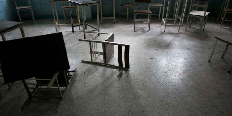 Fotografía del 1 de junio de 2016 muestra sillas y escritorios en un salón de clases abandonado en una escuela secundaria pública en Caracas, Venezuela. Oficialmente, Venezuela canceló este año 16 días de escuela, incluyendo clases del viernes, debido a una crisis de producción de electricidad. En realidad, los niños venezolanos están perdiendo ahora un promedio de 40% de tiempo de clases, calculó un grupo de padres de familia, y una tercera parte de los maestros falta a clases cualquier día dado para formarse en filas para conseguir alimento. (AP Foto/Ariana Cubillos)