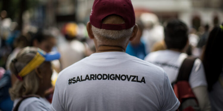 AME1938. CARACAS (VENEZUELA), 01/05/2024.- Un hombre con una camisetas con la etiqueta de #SalarioDignoVzla sale a las calles con para participar en una manifestación en conmemoración del Día Internacional del Trabajo este miércoles, en Caracas (Venezuela). Sindicatos y trabajadores de Venezuela salen a las calles a protestar para exigir un incremento de sus salarios y mejoras en los beneficios laborales. EFE/ Miguel Gutiérrez