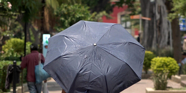 MEX7690. OAXACA (MÉXICO), 14/06/2023.- Una persona se protege del sol con una sombrilla el 13 de junio de 2023, debido a las altas temperaturas registradas en el estado de Oaxaca (México). La ola de calor que azota a México se extiende este miércoles, cuando 22 de las 32 entidades del país esperan temperaturas mayores a los 40 grados, según el Servicio Meteorológico Nacional (SMN). EFE/Jesús Méndez