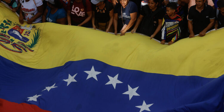 AME9271. CARACAS (VENEZUELA), 04/07/2024.- Seguidores del presidente venezolano Nicolás Maduro sostienen una bandera de Venezuela este jueves, en Caracas (Venezuela). Comienza oficialmente la campaña electoral para las presidenciales del 28 de julio, en las que se medirán diez candidatos, entre ellos el actual presidente, Nicolás Maduro, y el abanderado de la mayor coalición opositora -la Plataforma Unitaria Democrática (PUD)-, Edmundo González Urrutia, quienes ya llevan semanas de precampaña con actos proselitistas por diversos estados del país. EFE/ Miguel Gutiérrez