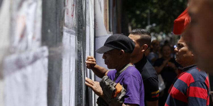 AME5617. CARACAS (VENEZUELA), 28/07/2024.- Ciudadanos venezolanos buscan su mesa de votación durante la jornada de elecciones presidenciales de Venezuela este domingo, en Caracas (Venezuela). El CNE informó este domingo que, sobre las 08.00 hora local (12.00 GMT), el 95 % de los 15.797 centros de votación ya estaban abiertos -dos horas más tarde la hora oficial fijada para la apertura- y computando los votos de personas que acudieron desde muy temprano a las urnas. EFE/ Henry Chirinos